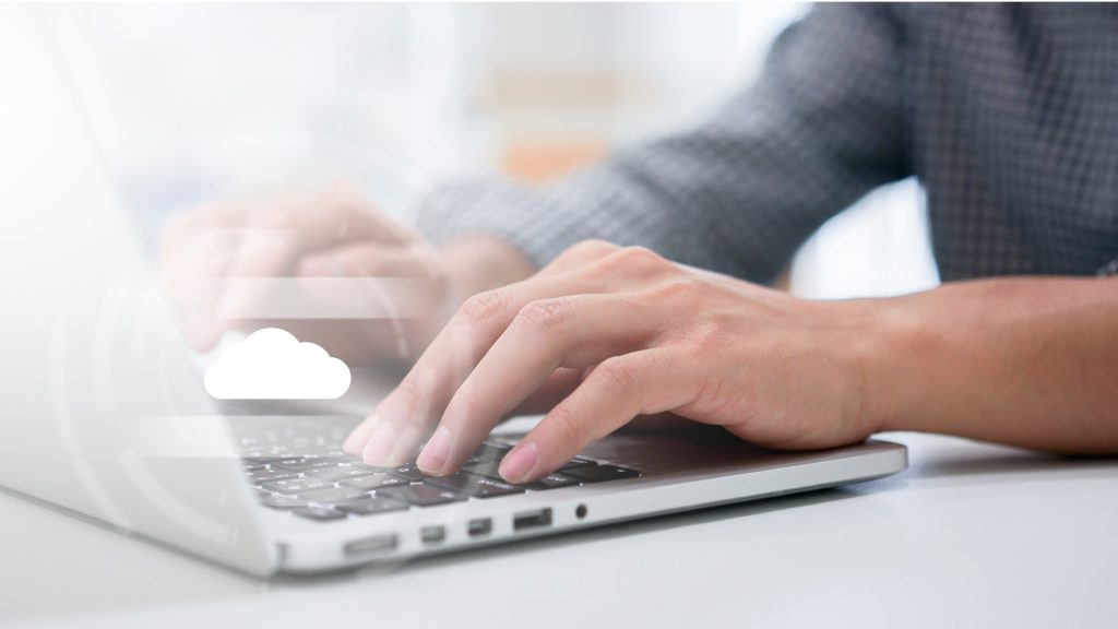 a person types on a laptop computer as it syncs to the cloud