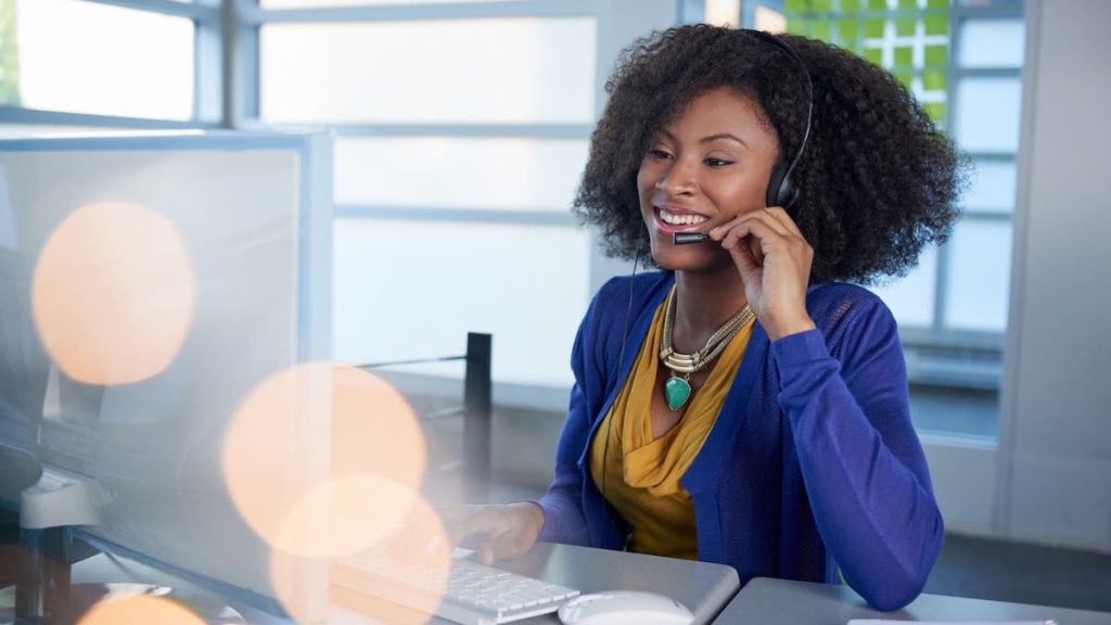 Smiling customer service agent talking on headset in front of computer | Linkpoint360