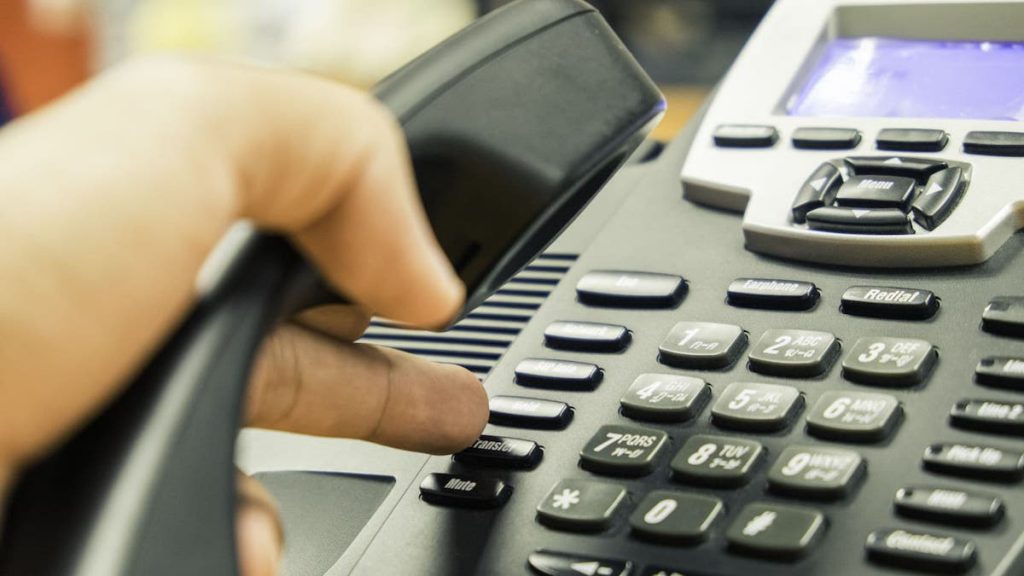 Close up of sales rep dialing on a desk phone | Linkpoint360