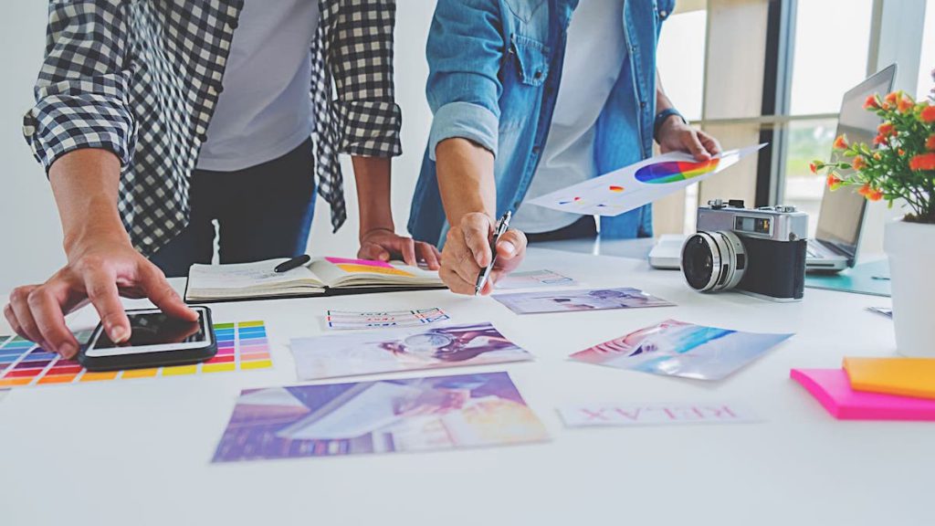 Close up of two marketers leaning over colorful data reports on white table | Linkpoint360