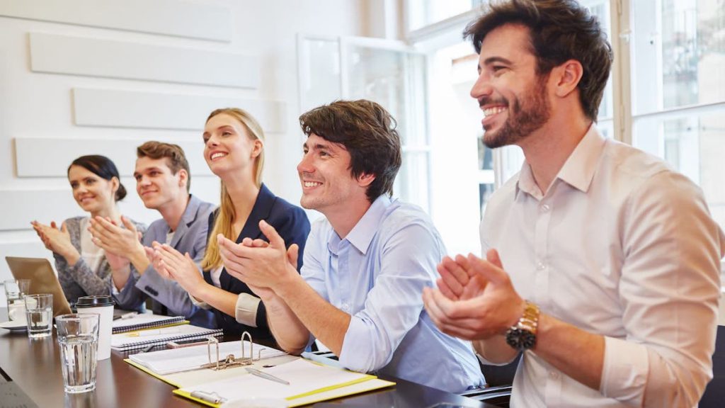 Five smiling employees clap while sitting at conference table | clean data | Linkpoint360