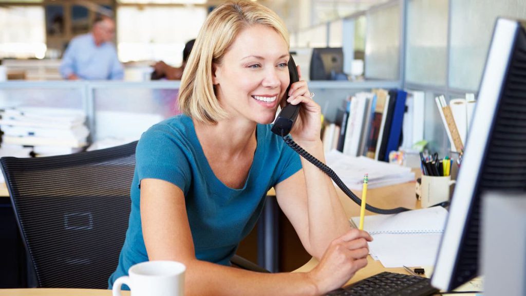 Woman with short, blonde hair sits in her cubicle while smiling and talking on her desk phone | clean data | Linkpoint360