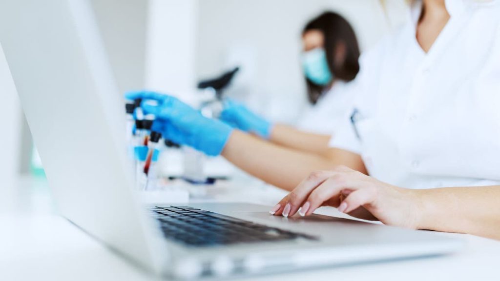 Close up of person in blue latex gloves typing on laptop computer | data cleaning | Linkpoint360