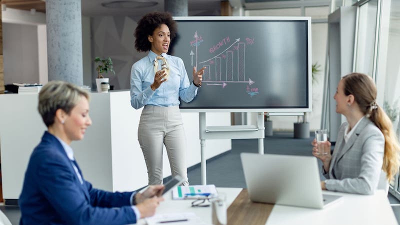 Manager stands near blackboard reviewing growth chart during meeting | Organizing customer data in a CRM