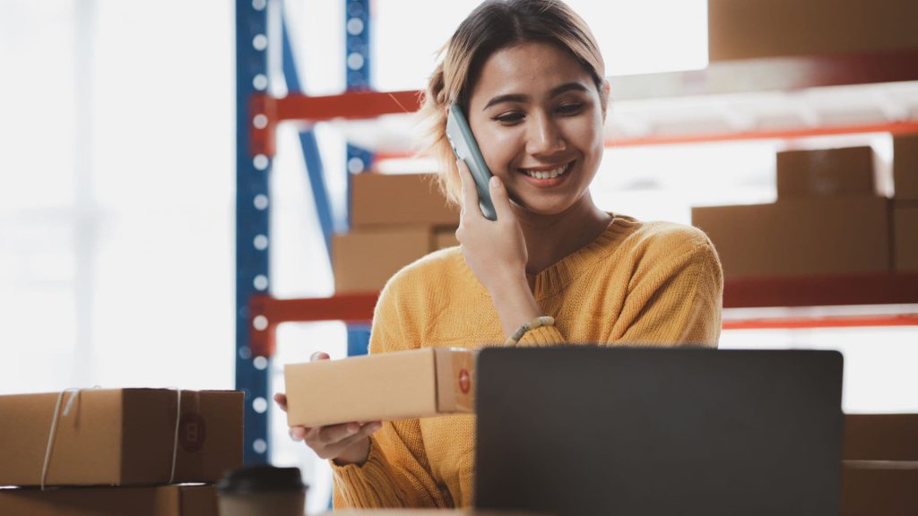 Woman Smiles While Talking on the Phone and Preparing Shipment in Warehouse | AI and Salesforce