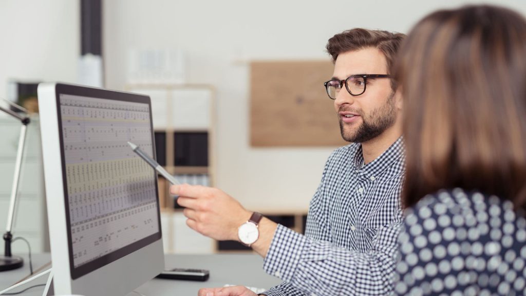 Sales Manager Points at Computer Screen While Discussing Processes With Employee | AI and Sales Enablement