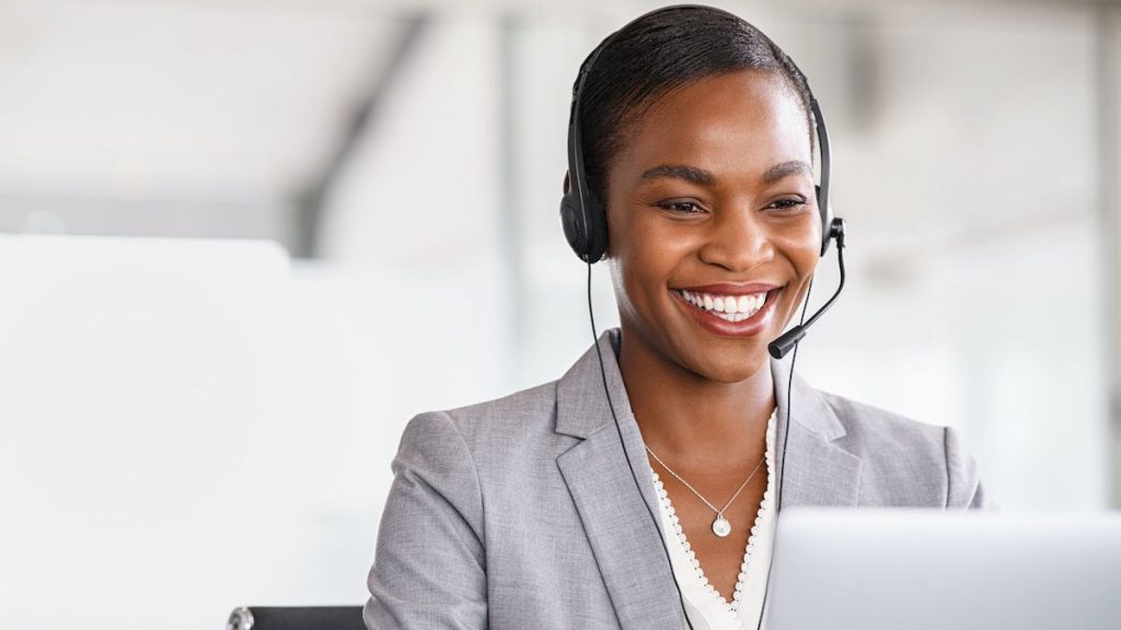 Salesperson wearing headset smiles while following up with customer | CRM tips and tricks